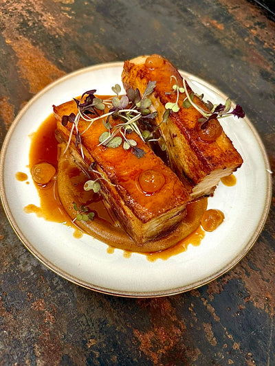 Crispy pork belly tapas served on a plate with garnish